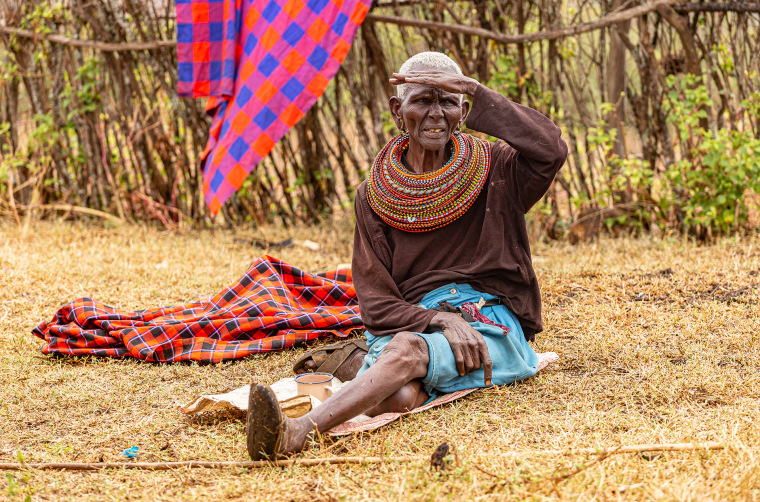 Starší žena kmene Samburu odpočívá u své chýše